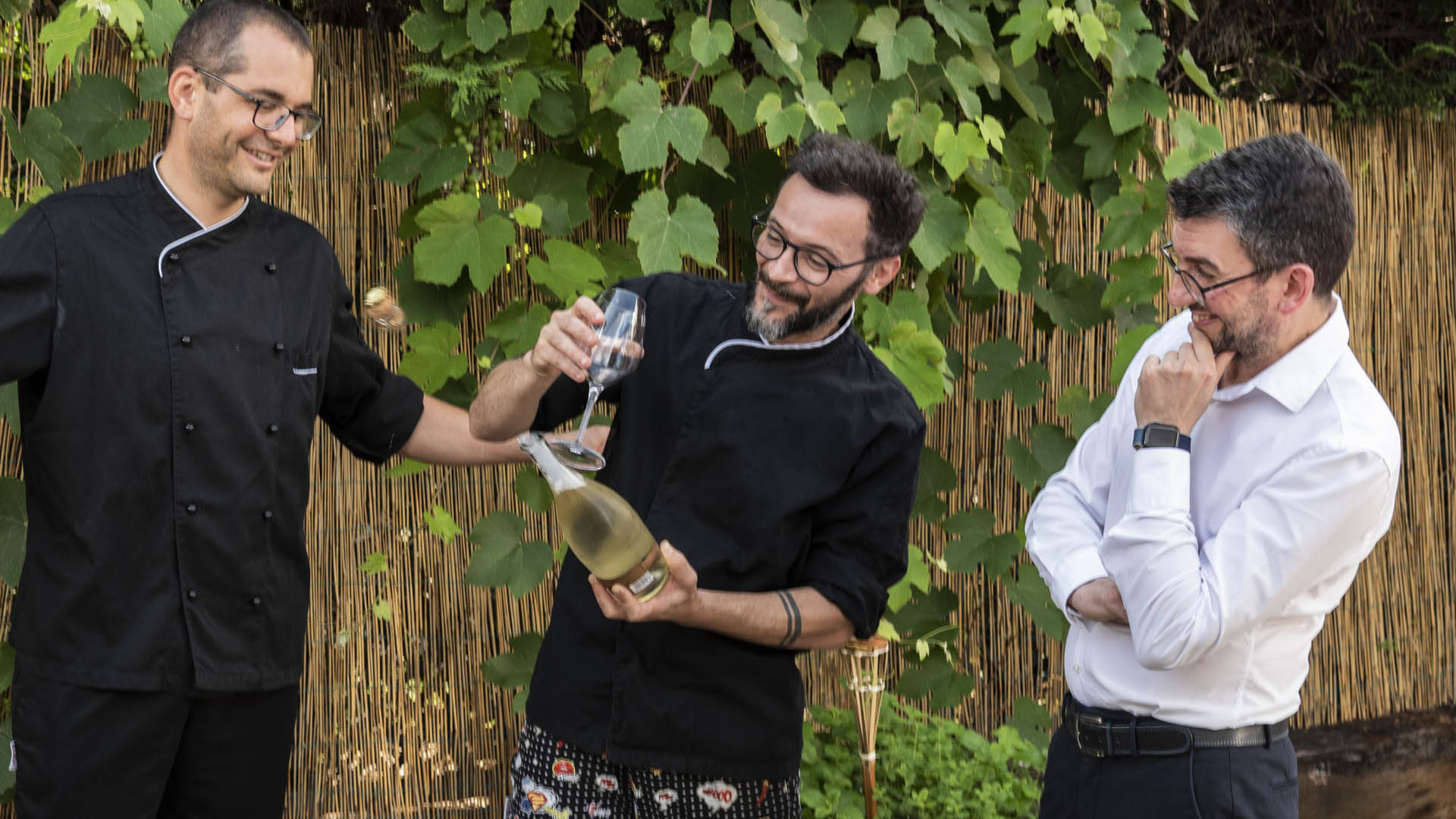 Three friends and Fillet customers smiling and opening a bottle of wine.